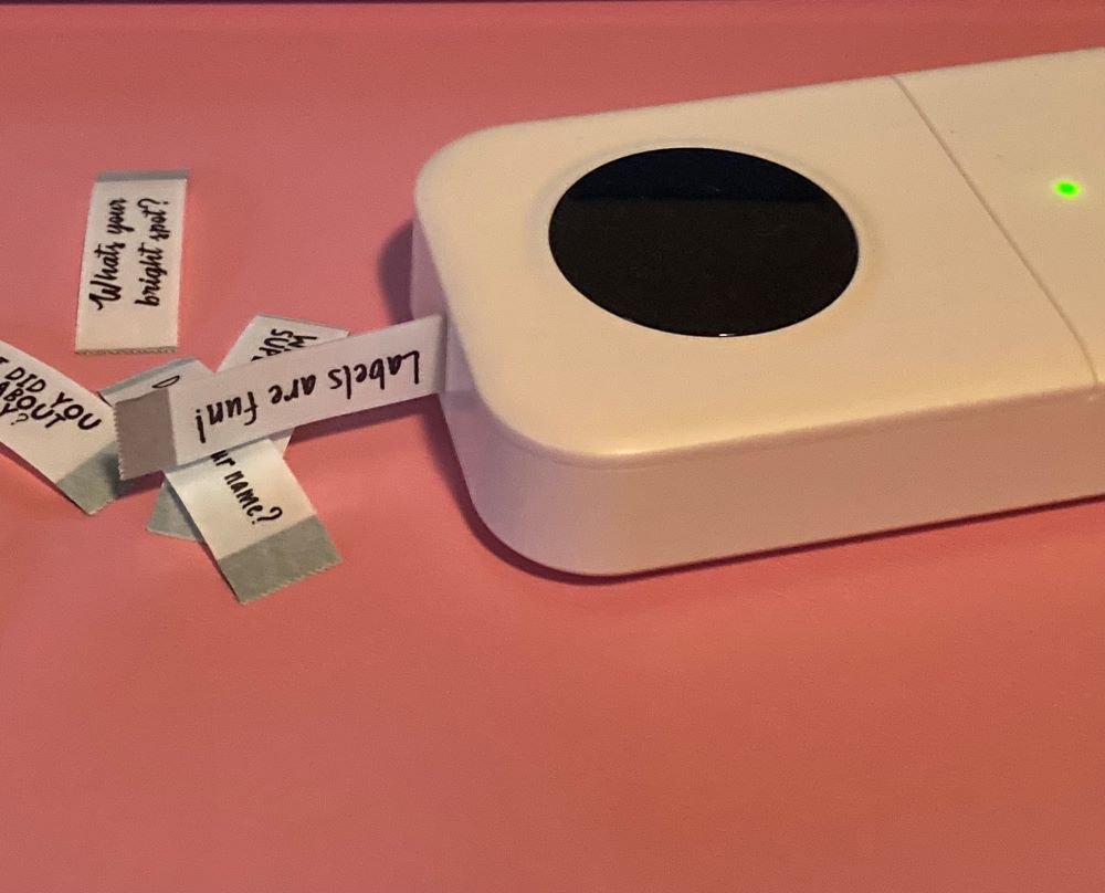 Phomemo D30 label maker and labels on pink background